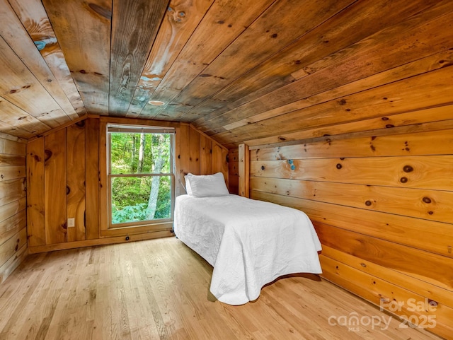 unfurnished bedroom featuring wood ceiling, wood finished floors, wooden walls, and vaulted ceiling