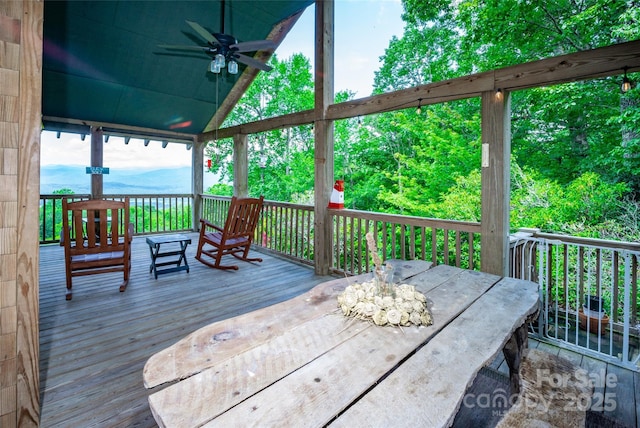 wooden deck with a mountain view, ceiling fan, and outdoor dining area