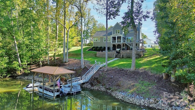 view of dock featuring a deck with water view and a lawn