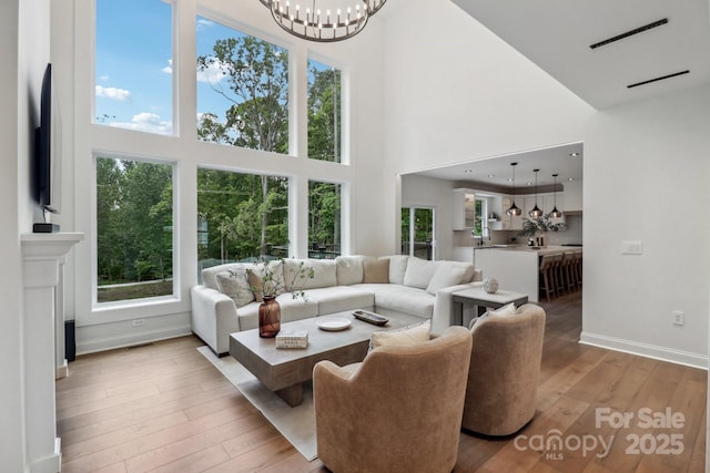 living room with a high ceiling, wood-type flooring, healthy amount of natural light, and baseboards