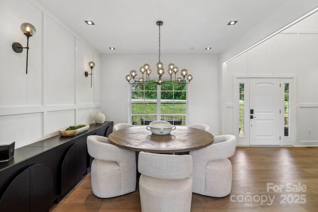 dining room featuring wood finished floors, a chandelier, and a decorative wall