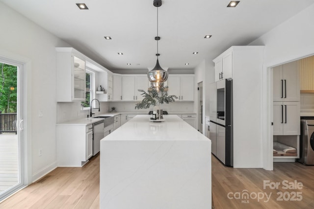 kitchen with light wood-type flooring, stainless steel appliances, a center island, white cabinetry, and recessed lighting