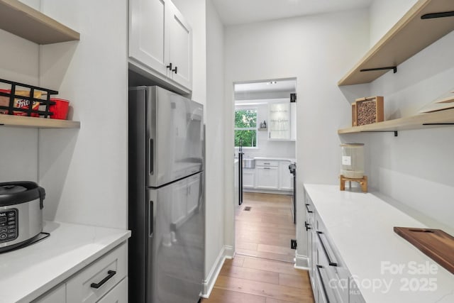 kitchen featuring freestanding refrigerator, open shelves, light wood-style floors, and white cabinetry