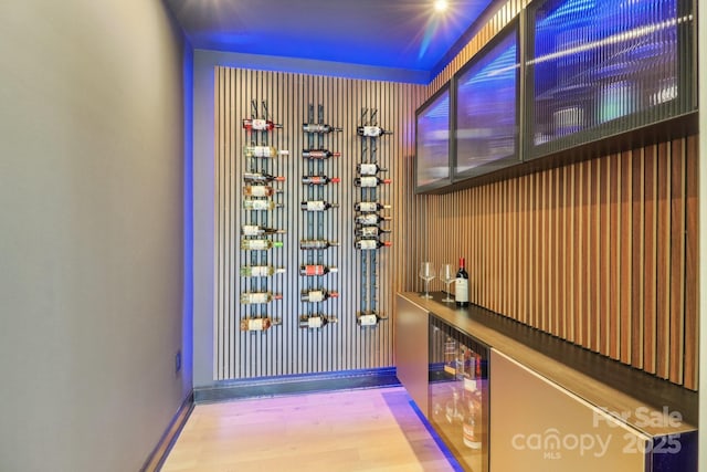 wine room with beverage cooler, wood finished floors, and baseboards