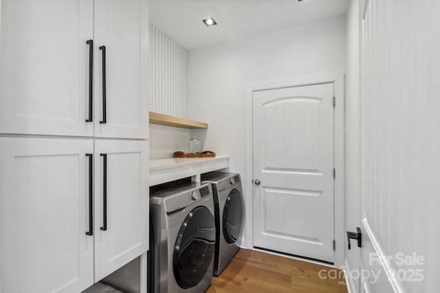 laundry room featuring washer and clothes dryer, cabinet space, and wood finished floors