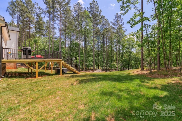 view of grassy yard featuring stairs and a wooden deck