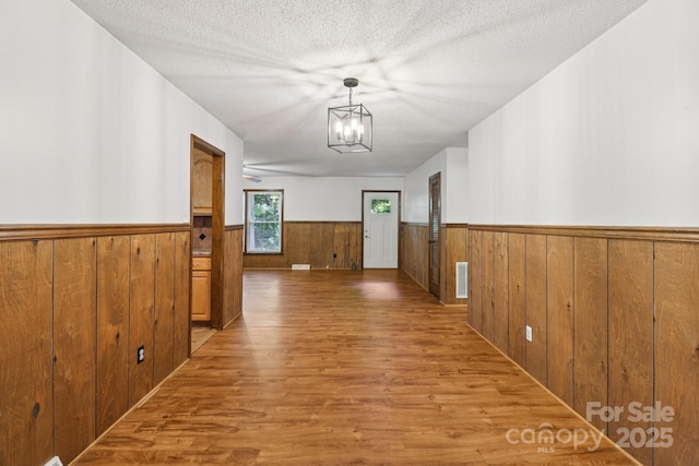 119 Legacy Ln, Harmony, NC 28634 - hall with a wainscoted wall, light wood-style floors, wooden walls, a chandelier, and a textured ceiling