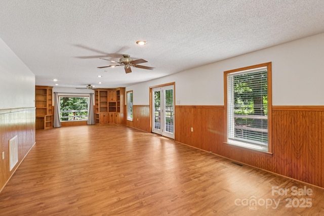 119 Legacy Ln, Harmony, NC 28634 - unfurnished room with wainscoting, light wood finished floors, a textured ceiling, a ceiling fan, and wood walls