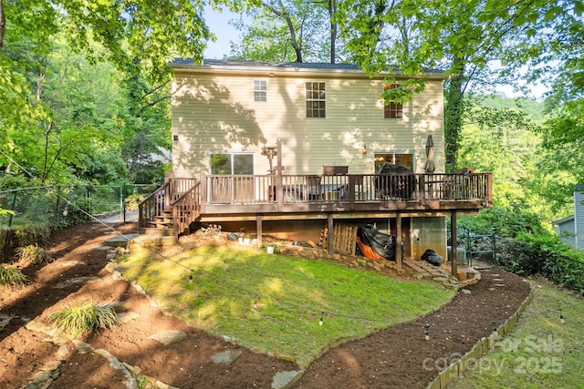 back of property with fence, a deck, and stairway