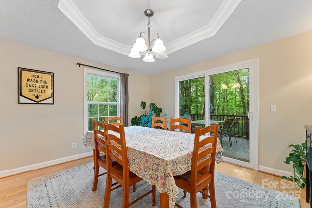 dining space featuring baseboards, a chandelier, ornamental molding, and light wood finished floors