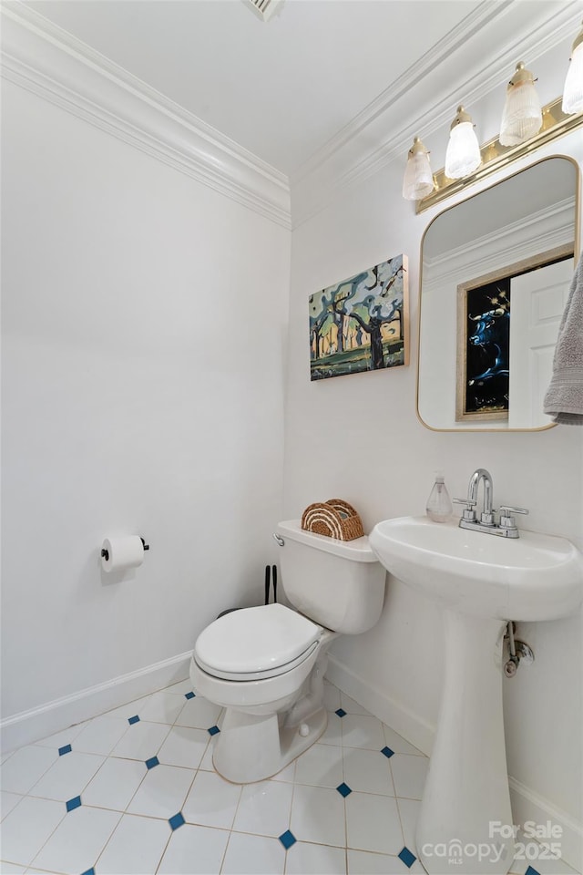 half bathroom featuring a sink, baseboards, ornamental molding, and toilet