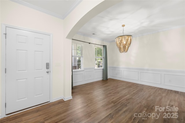 17413 Caddy Ct, Charlotte, NC 28278 - entrance foyer with arched walkways, wood finished floors, a chandelier, a wainscoted wall, and ornamental molding