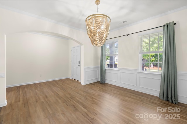 17413 Caddy Ct, Charlotte, NC 28278 - unfurnished dining area with arched walkways, ornamental molding, a chandelier, wood finished floors, and wainscoting