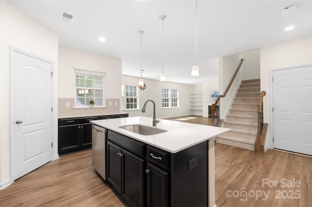 17413 Caddy Ct, Charlotte, NC 28278 - kitchen featuring dark cabinets, light wood-type flooring, light countertops, stainless steel dishwasher, and backsplash