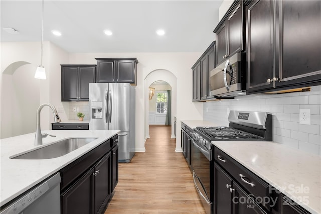 17413 Caddy Ct, Charlotte, NC 28278 - kitchen with appliances with stainless steel finishes, arched walkways, light wood finished floors, hanging light fixtures, and light stone countertops