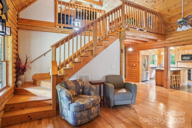 10583 Earnhardt Lake Rd, Davidson, NC 28036 - living area featuring rustic walls, light wood-style flooring, high vaulted ceiling, stairway, and wood ceiling