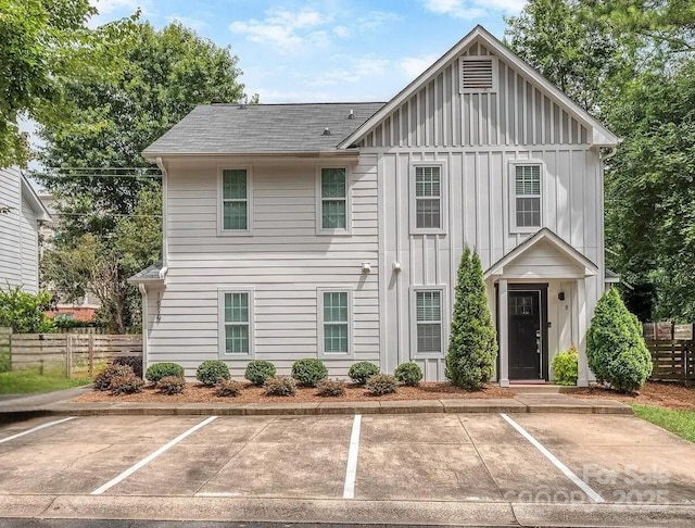 view of front of home featuring uncovered parking, board and batten siding, and fence