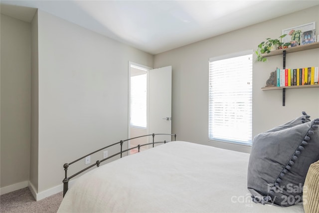 carpeted bedroom featuring baseboards and multiple windows