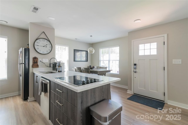 kitchen featuring a peninsula, light wood-style floors, modern cabinets, light countertops, and appliances with stainless steel finishes