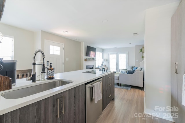 kitchen featuring light wood-style flooring, light countertops, a sink, modern cabinets, and dishwasher