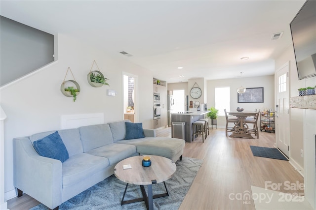 living area featuring baseboards, visible vents, recessed lighting, and light wood-style floors