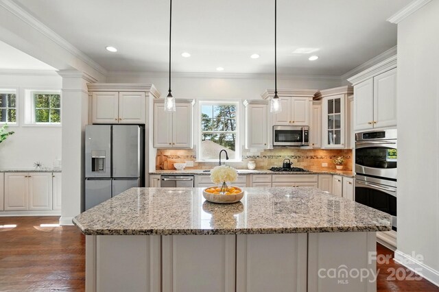 404 Brookridge Dr, Mount Holly, NC 28120 - kitchen with appliances with stainless steel finishes, a center island, healthy amount of natural light, backsplash, and ornamental molding