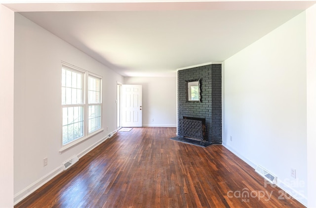 unfurnished living room with dark wood-style flooring, visible vents, baseboards, and a brick fireplace