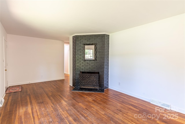unfurnished living room featuring baseboards, wood finished floors, a fireplace, and visible vents