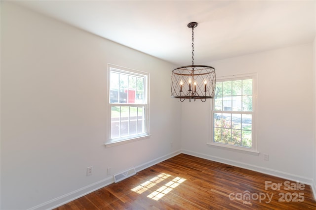 unfurnished room featuring dark wood-type flooring, visible vents, baseboards, and an inviting chandelier
