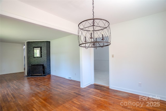 unfurnished dining area featuring visible vents, baseboards, an inviting chandelier, and wood finished floors
