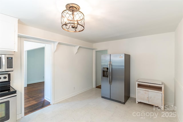 kitchen with white cabinets, a notable chandelier, baseboards, and appliances with stainless steel finishes