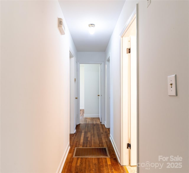 hall featuring wood finished floors, baseboards, and visible vents