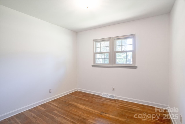 spare room with visible vents, baseboards, and wood finished floors