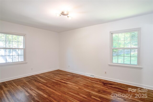 spare room featuring visible vents, baseboards, and wood finished floors