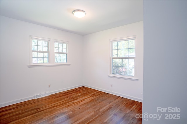 empty room with visible vents, baseboards, and wood finished floors