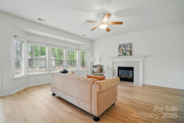 212 Kilborne Rd, Mooresville, NC 28117 - living area with baseboards, light wood-style floors, visible vents, ceiling fan, and a tile fireplace