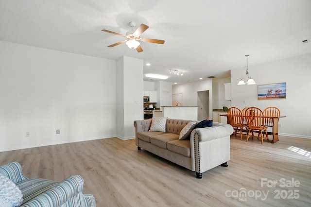 212 Kilborne Rd, Mooresville, NC 28117 - living room featuring light wood-style flooring, recessed lighting, baseboards, and ceiling fan with notable chandelier