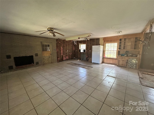 unfurnished living room with light tile patterned flooring, a textured ceiling, and ceiling fan