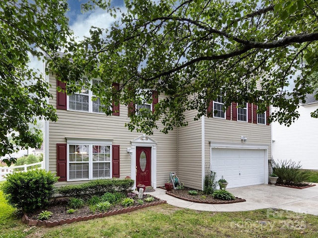 colonial-style house with an attached garage, a front yard, concrete driveway, and fence