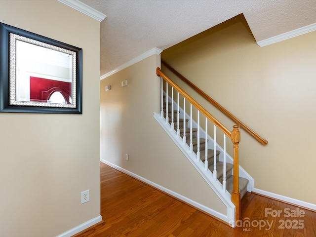 staircase with baseboards, crown molding, and wood finished floors