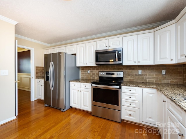 kitchen featuring stainless steel appliances, light wood-type flooring, crown molding, tasteful backsplash, and white cabinetry