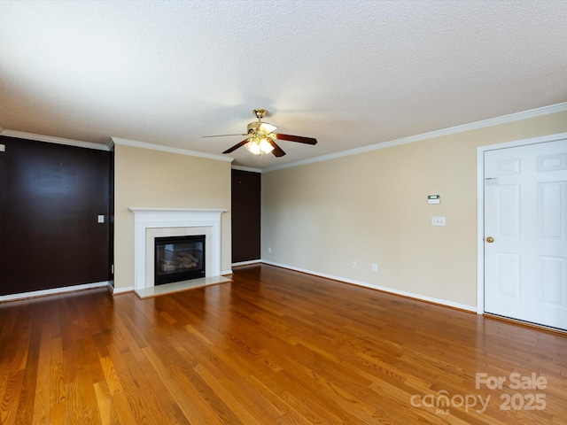 unfurnished living room featuring a glass covered fireplace, a ceiling fan, wood finished floors, and crown molding