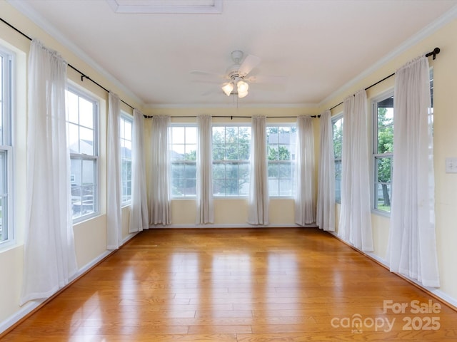 unfurnished sunroom featuring ornamental molding, wood finished floors, and plenty of natural light