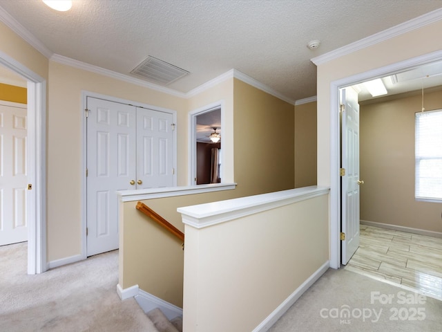 hallway featuring baseboards, visible vents, an upstairs landing, and light colored carpet