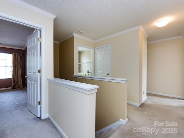 corridor featuring an upstairs landing, a textured ceiling, light colored carpet, baseboards, and ornamental molding