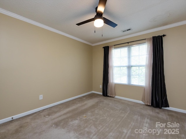spare room with crown molding, ceiling fan, carpet, baseboards, and visible vents