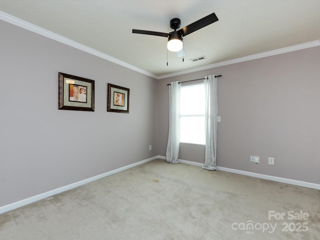 empty room featuring visible vents, a ceiling fan, ornamental molding, carpet floors, and baseboards