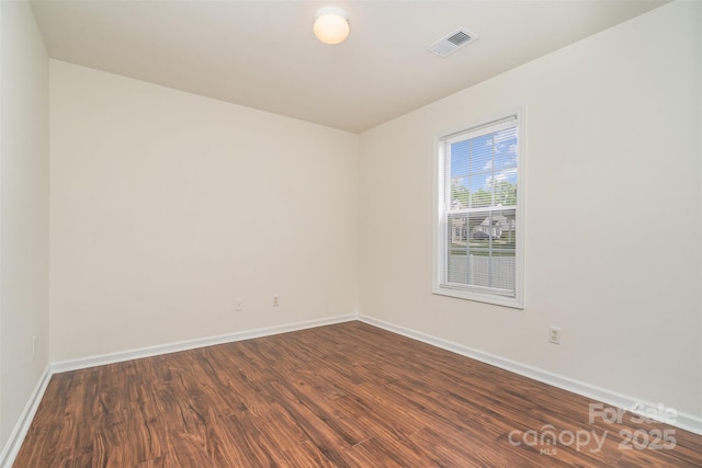 unfurnished room featuring visible vents, baseboards, and dark wood finished floors