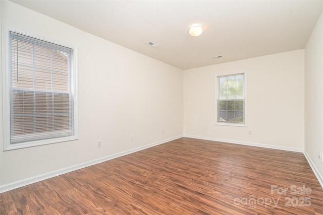 spare room featuring visible vents, baseboards, and wood finished floors