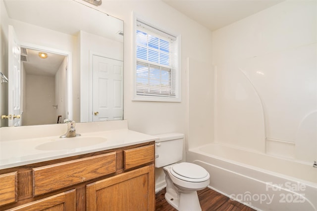 bathroom featuring toilet, shower / washtub combination, vanity, and wood finished floors